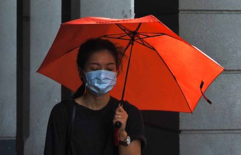 Perempuan Wan Chai, Hong Kong, melintas dengan masker saat pandemi Covid-19 (foto: Tam Wai | unsplash)